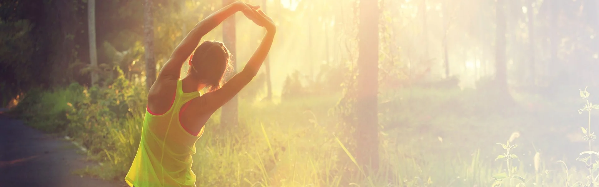 Back of a woman' stretching sideways in sunshine in a park » HCi