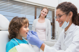 Female dentist looking at child's teeth with mum in the background » HCi