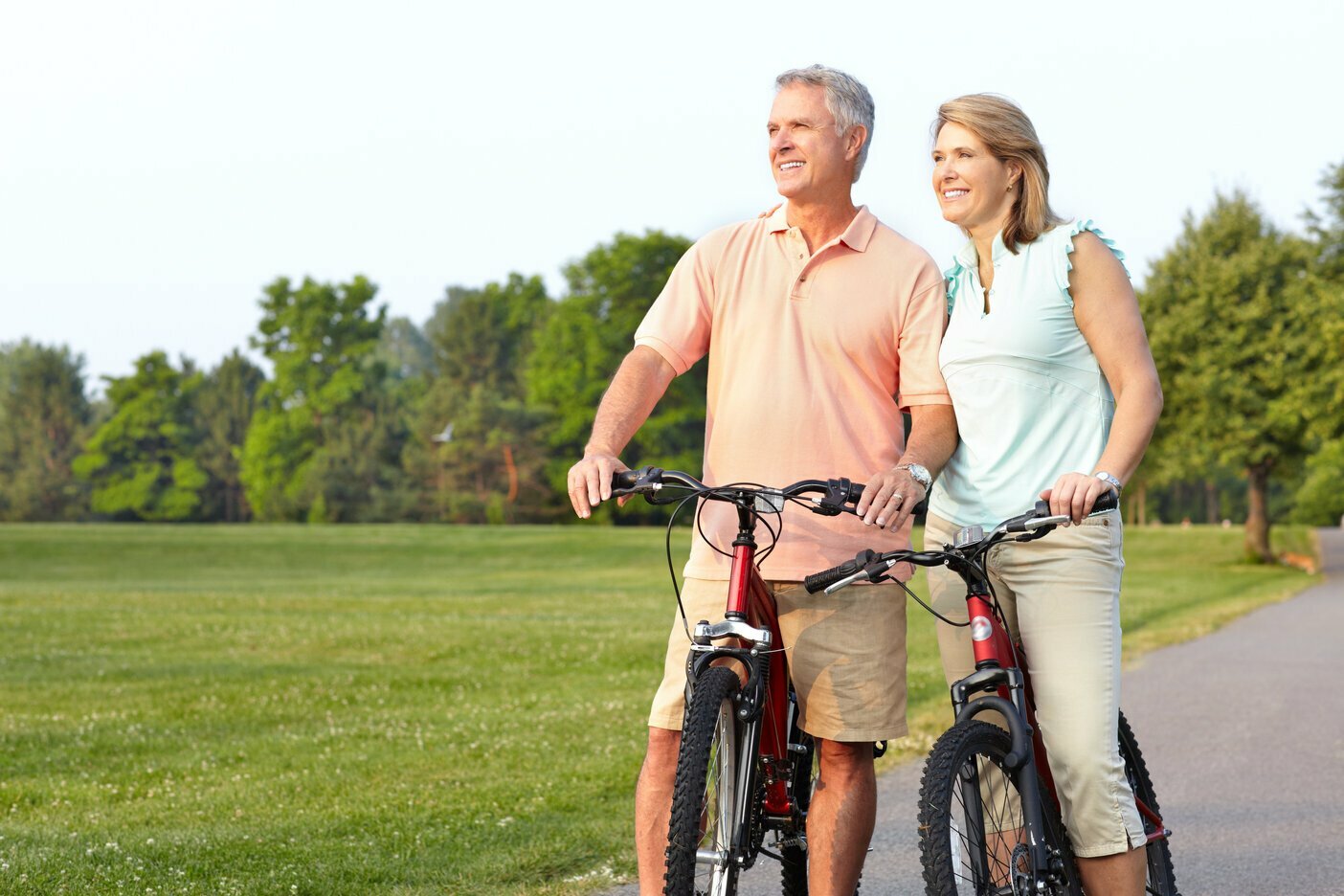 Mature couple on bikes looking across a grassy park, being healthy and secure with HCi health cover
