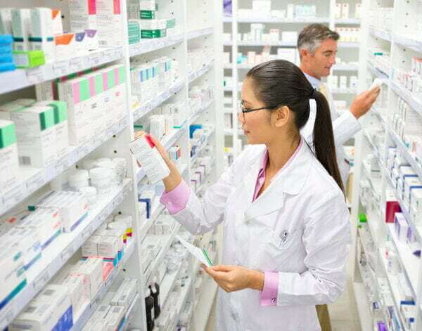 Two pharmacists selecting prescription medicines off shelves, ahead of HCi members' pharmacy claims » HCi