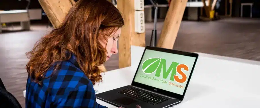 Woman looking at the screen of a laptop which shows the HCi OMS logo - accessing OMS for claiming and to manage her HCi membership