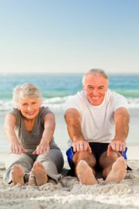 Couple at the beach stretching to their toes for health and ahealthy weight for life and a strong heart